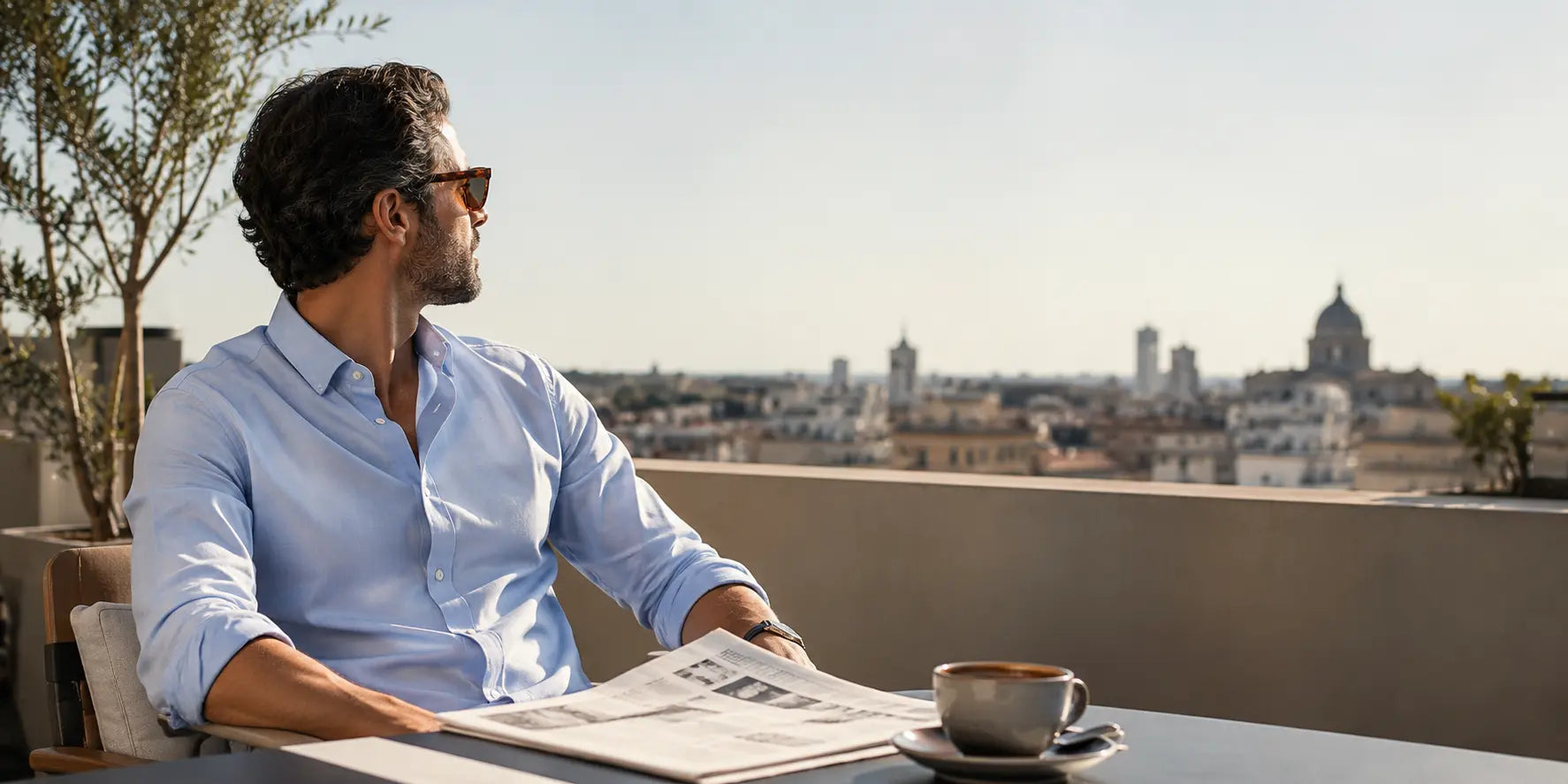 Hombre con camisa azul clara disfrutando de una mañana relajada en una terraza urbana