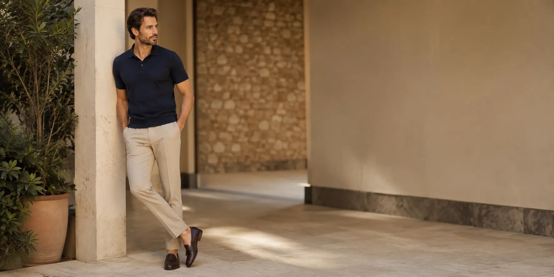 Hombre con polo azul marino y pantalón beige en un look elegante de verano masculino.