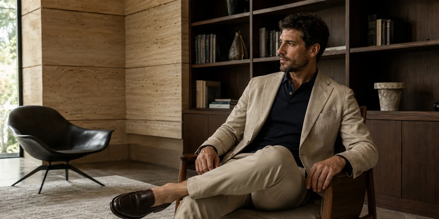 Hombre con polo azul marino y americana beige en un interior elegante