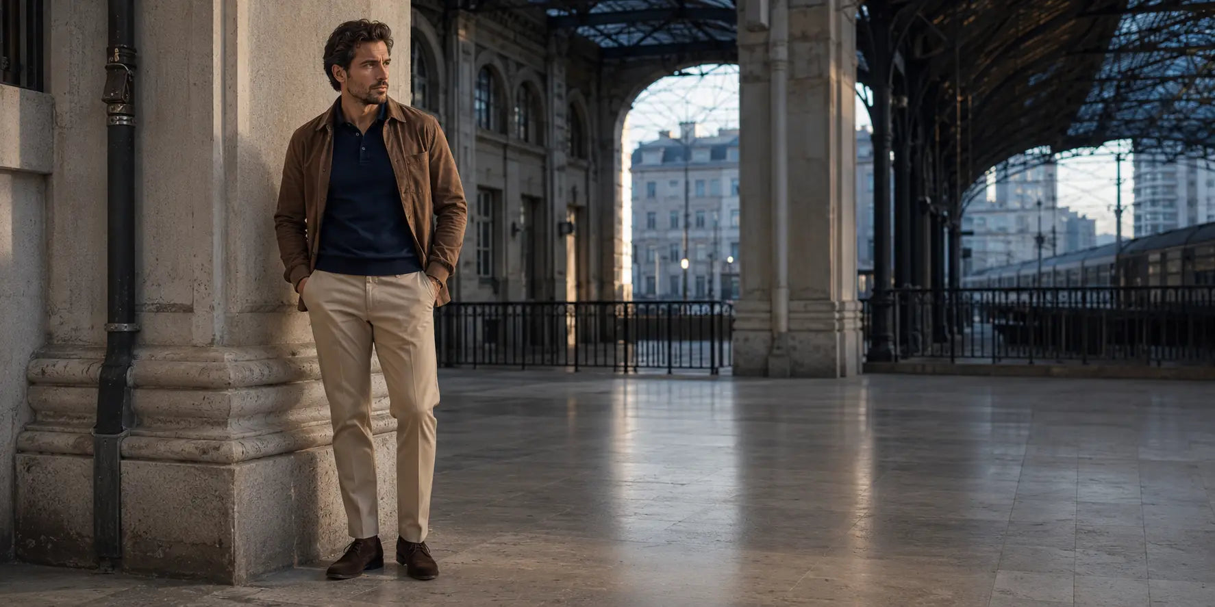 Hombre con polo azul marino, pantalón chino beige y sobrecamisa marrón en un look de entretiempo.