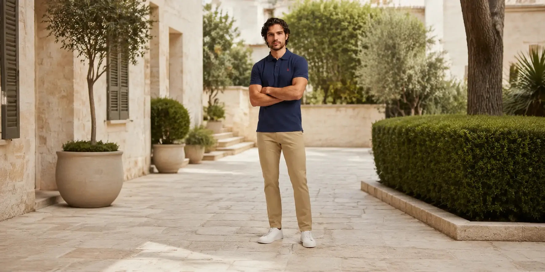 Hombre con polo azul marino Bakes y pantalón chino beige en un look de armario funcional