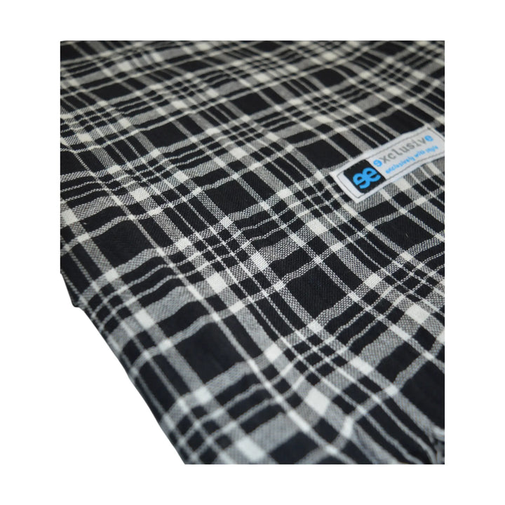 Detalle del tejido y etiqueta de la bufanda Pazos negra de cuadros