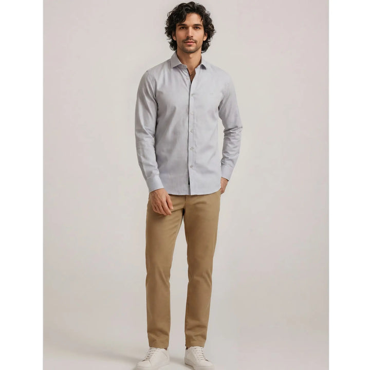 Hombre con camisa azul clara de manga larga y pantalón beige en un outfit urbano premium