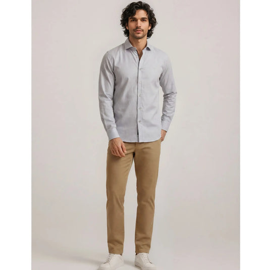 Hombre con camisa azul clara de manga larga y pantalón beige en un outfit urbano premium