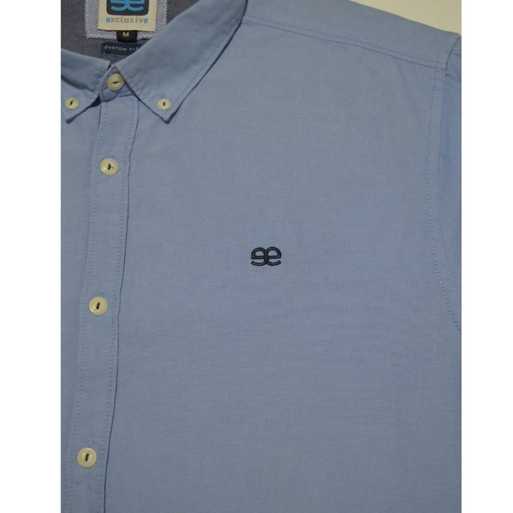 Detalle logo bordado en camisa azul hombre acabado limpio y discreto