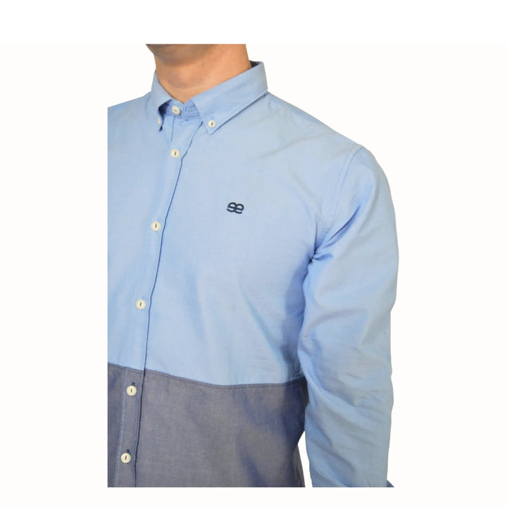 Detalle del logo bordado en camisa azul bicolor para hombre de EE Exclusive, fondo blanco.