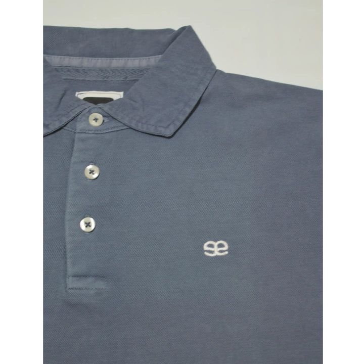 Detalle del tejido y logo bordado del polo azul jeans Asse de EE Exclusive con acabado premium y estilo masculino elegante
