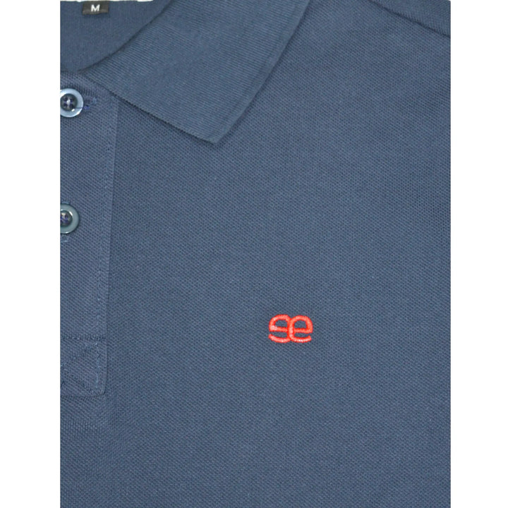 Detalle del tejido y logo del polo azul marino Bakes EE Exclusive, acabado premium y diseño cuidado