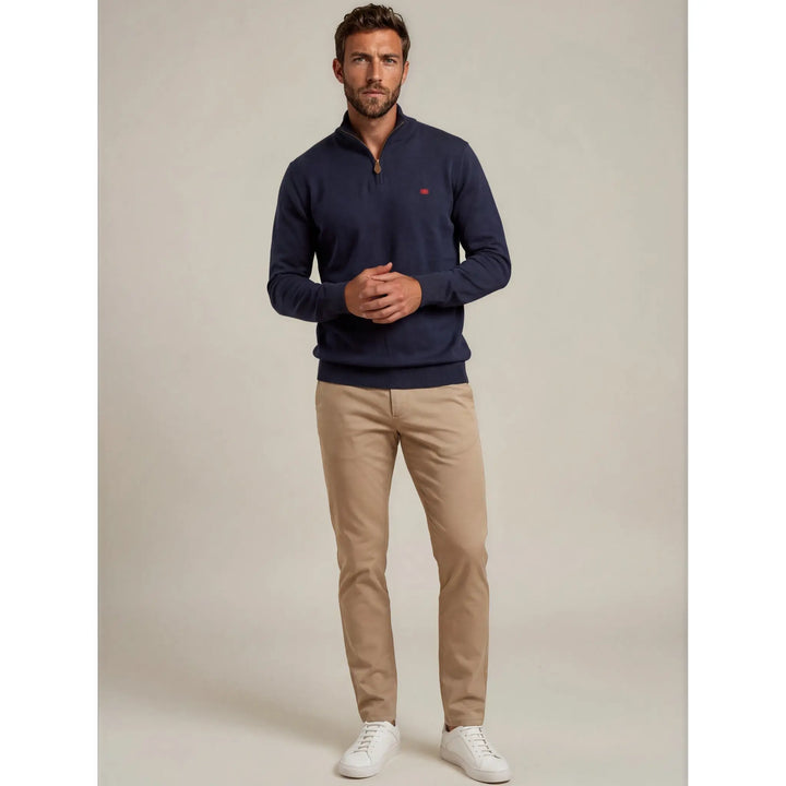 Hombre con jersey azul marino Kilagi de media cremallera combinado con pantalón beige y zapatillas blancas
