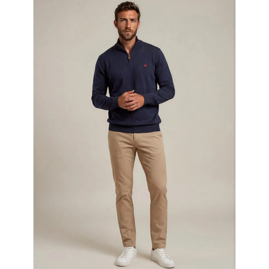 Hombre con jersey azul marino Kilagi de media cremallera combinado con pantalón beige y zapatillas blancas