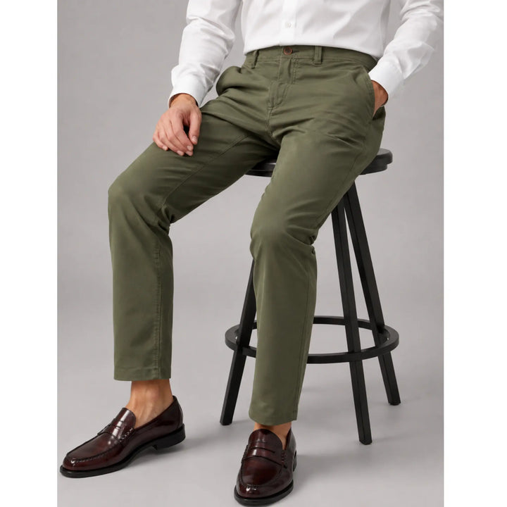 Pantalón Distan verde para hombre sentado mostrando la caída y flexibilidad del tejido
