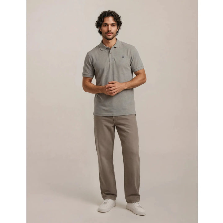 Hombre combinando polo gris premium con vaquero beige y zapatillas blancas en un estilo urbano sofisticado